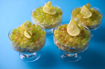 meat chicken salad in layers in a transparent glass with green grapes and lemon slices next to kiwi on a blue background. for labels, screensavers, business cards, banners, menu signs