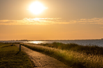 Fototapeta na wymiar golden hour evening panorama with cobblestone path at coast line at marken island