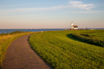 Fototapeta na wymiar stone path guiding towards paard van marken lighthouse on marken island in golden hour