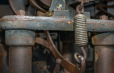 Close-up of a shiny steel spring as part of an unknown heavy machine that has been disused for a...