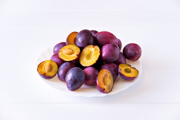 Fresh ripe plum cut in half in a plate with pits.