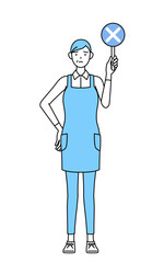 不正解を示すバツの棒を持つエプロンを着たシニア女性