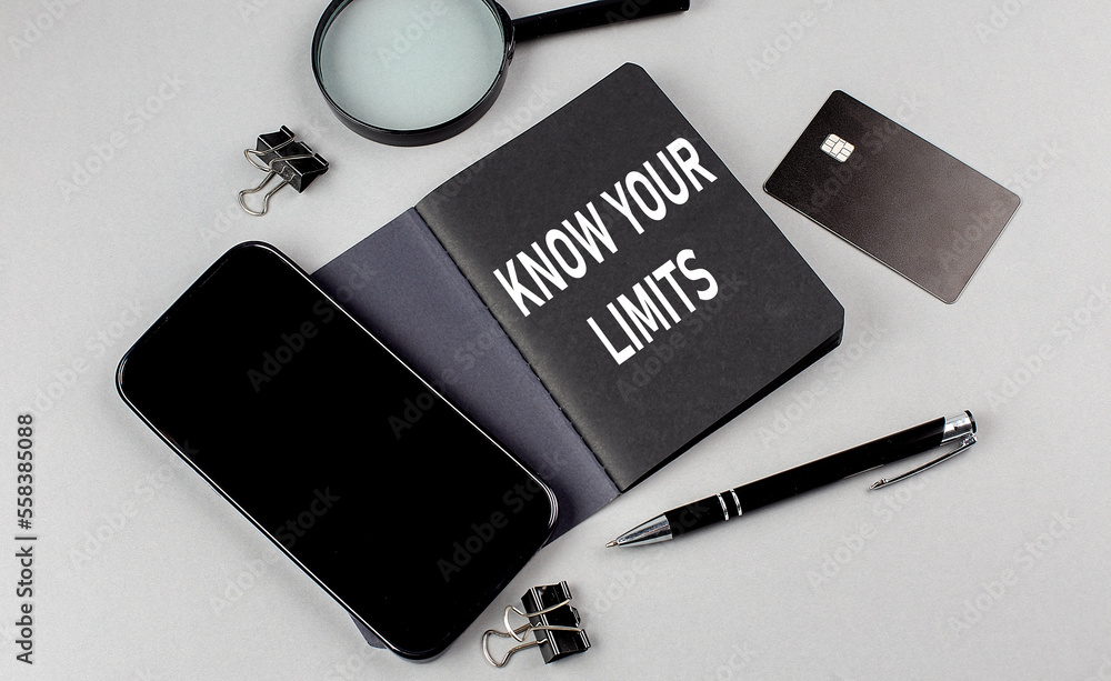 Poster know your limits text written on black notebook with smartphone, magnifier and credit card