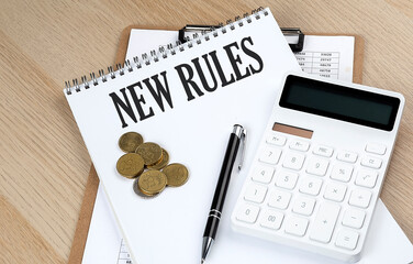 NEW RULES text on a notebook with chart and calculator and coins, business concept