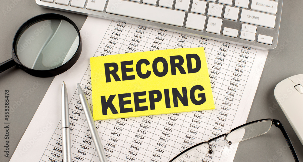 Poster record keeping text written on a sticky on chart with keyboard and magnifier