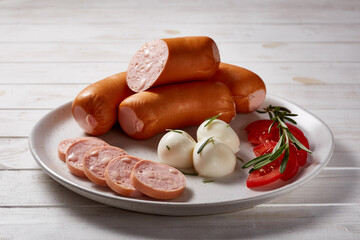 Beautifully decorated platter of sausages, sliced, with bread, vegetables, herbs, eggs, sauces on a...