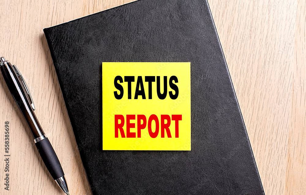Poster status report text on a sticky on black notebook with pen