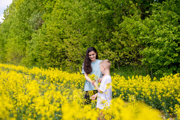 Fototapeta premium A cute boy in a white T-shirt gives his mother yellow flowers