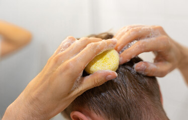 A man applies a solid shampoo bar to the hair. Sustainable hair care. Man in the bathroom. Plastic...