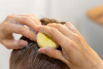 A man uses a solid shampoo bar in the bathroom. An applying shampoo to the scalp. Sustainable hair...