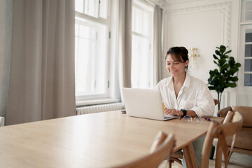 A freelancer woman is doing work on a startup, using a laptop. Workplace in a modern office.