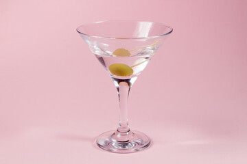 Martini glass with olive on a pink background. alcoholic drink
