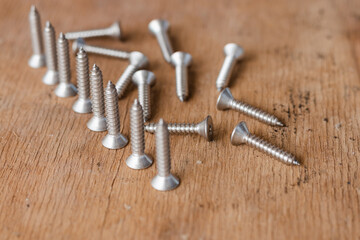 Tapping screws made of steel on table background, metal screw, iron screw, chrome screw, screws as a background, wood screw, concept industry. copy space for text.