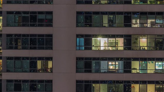 Windows lights in modern apartment buildings timelapse at night. Multi-level skyscrapers with illuminated rooms inside