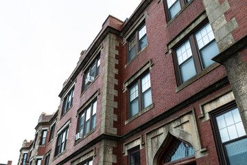 Beautifully featured architectural details on a classic old urban apartment building with corner quoins, leaded windows, and elaborate mouldings, horizontal aspect