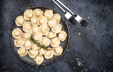 Traditional pelmeni, ravioli, dumplings with meat on a dark background. banner, menu, recipe place for text, top view.