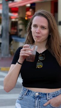 Young pretty woman has a cold drink in the sun of Miami Beach - travel photography