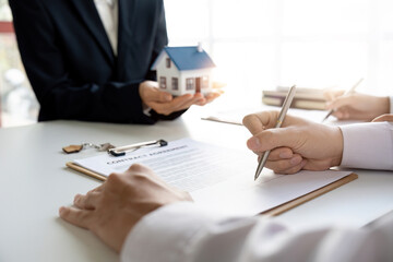 Real estate agent with couple closing a deal and signing a contract.