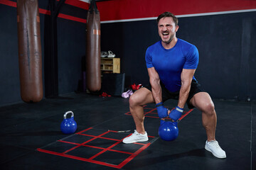 Fototapeta na wymiar athletic man training with kettlebell in the gym