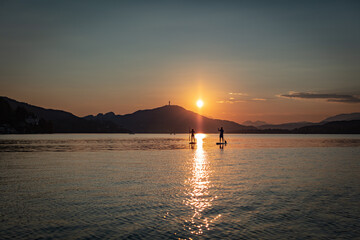 two stand up paddler at Woerther lake in carinthia during a beautiful summer sunset