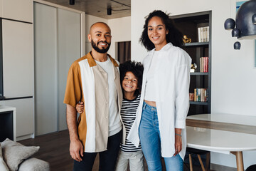 Happy black family with little son smiling and hugging together at home