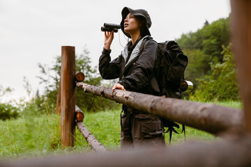 Young african woman tourist using binoculars during hiking in countryside