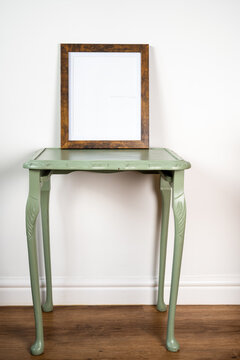 retro green table against a clean wall background and wooden floor with a picture photo frame mock up