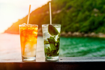 Glasses of Mai Tai and Mojito cocktails on the beach.