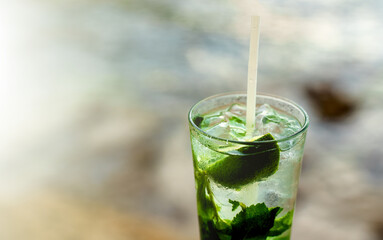 Glass of mojito in front of the sea background.