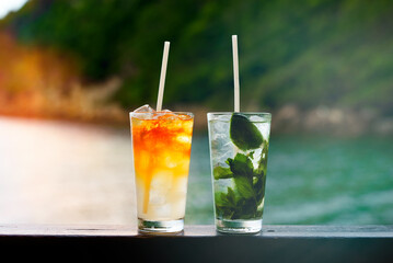 Glasses of Mai Tai and Mojito cocktails on the beach.