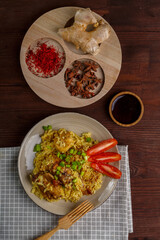 Fried chicken pieces in soy and pad thai sauce in a plate on a blue napkin on a table with spices.