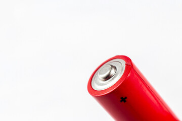 Bright red metal alkaline aa battery with plus sign on light background close up with copy space.
