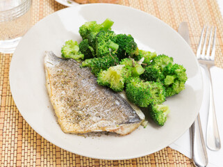 dish of fried dorado fish fillet with boiled broccoli