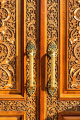 Fototapeta na wymiar Carved wooden doors with gilded metal handles..