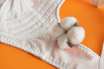 Fototapeta na wymiar cotton flower and white bra on orange background