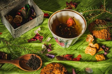 Still life- a cup of hot tea with medicinal herbs on a dark green background. Kitchen table...