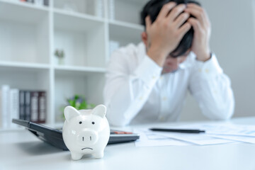 Stressed and headache asian man with large bills or invoices no money to pay to expenses and credit...