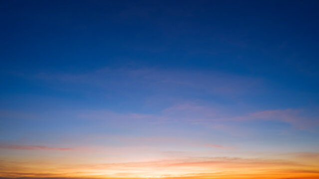 Dusk sky background with beautiful sunlight and sunset cloud after sundown on blue Twilight sky, idyllic peaceful nature background