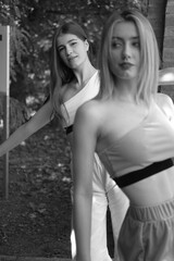 Naklejka premium Two girls walks at the summer park. pink and white wear. Black and white portraits