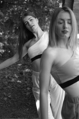 Fototapeta na wymiar Two girls walks at the summer park. pink and white wear. Black and white portraits