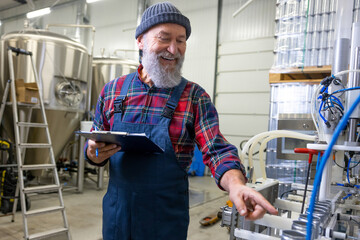 Cheerful production worker monitoring the drink canning process