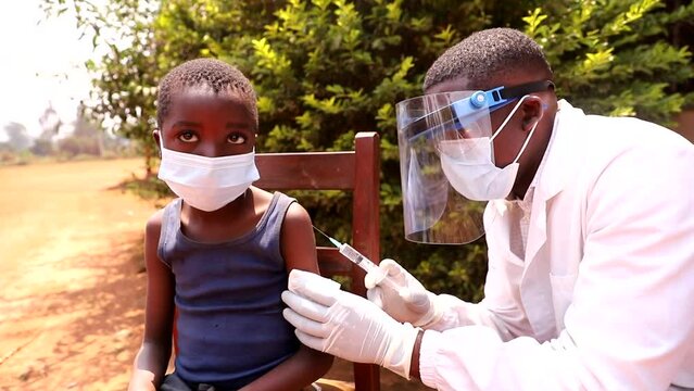 an African doctor injects the vaccine to a child. Coronavirus protection in africa concept.