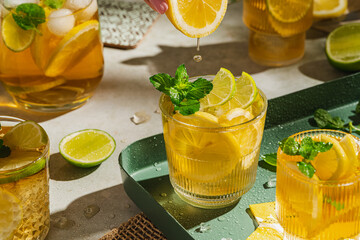 Traditional homemade iced tea with lemon, mint and ice in glasses. Summer cold drink on green...