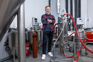 Man in plaid shirt working at the brewery and looking contented