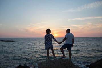 Obraz premium man and woman, he and she in full growth, silhouettes of couple in love against backdrop of sea and sunset stand holding hands. enjoyment of moment, tender feelings, pleasant pastime. Valentine's Day