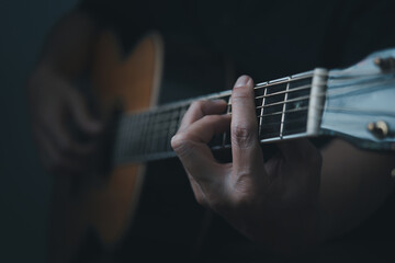 Close-up of a young man's hands playing an acoustic guitar