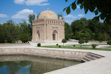 Samanid stone mausoleum in a park next to a swimming pool in Bukhara, Uzbekistan. Tourism, travel concept.