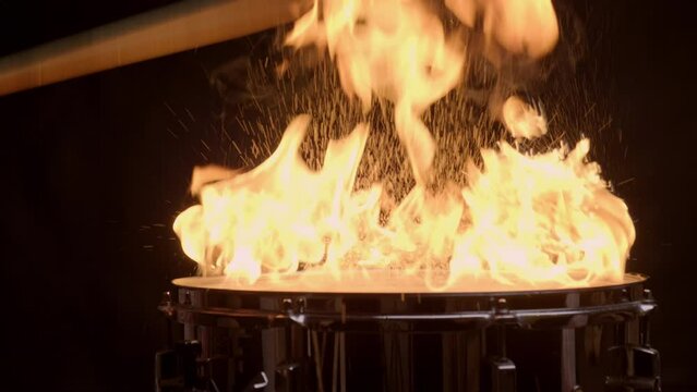 Musician plays drum kit burning in fire.