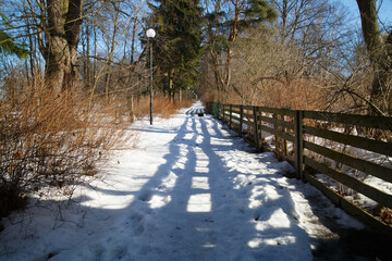 Shadow from the fence along the road in the countryside on a sunny winter day.