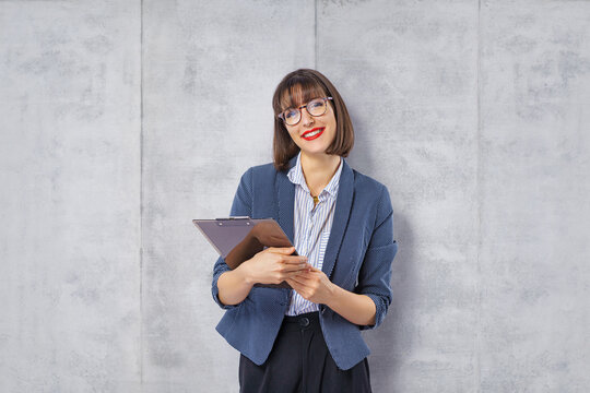  Pretty smiling business woman posing isolated grey wall background holding folder.